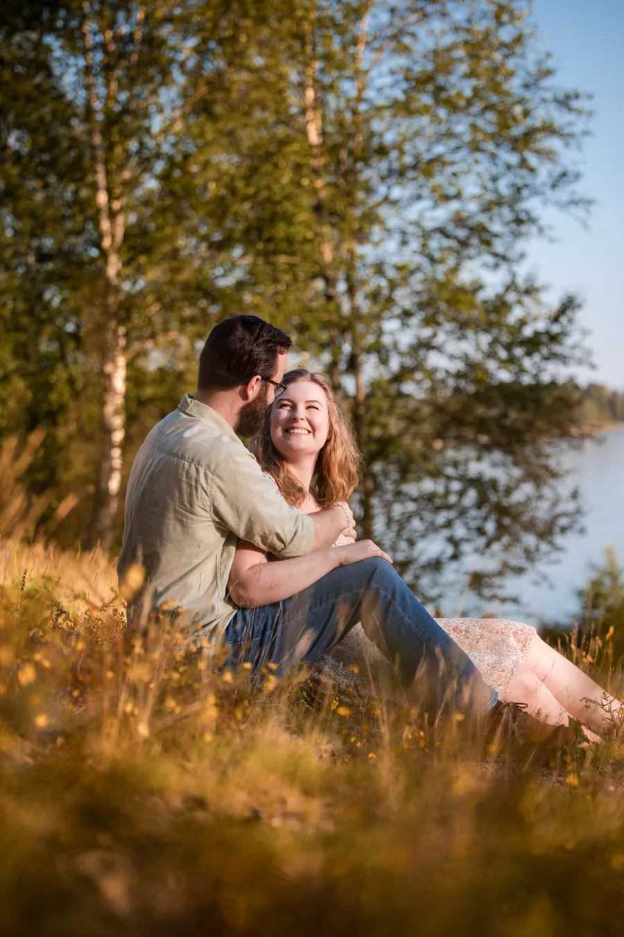 Turid og Erik sitter i sommergress ved Sognsvann med varmt kveldslys