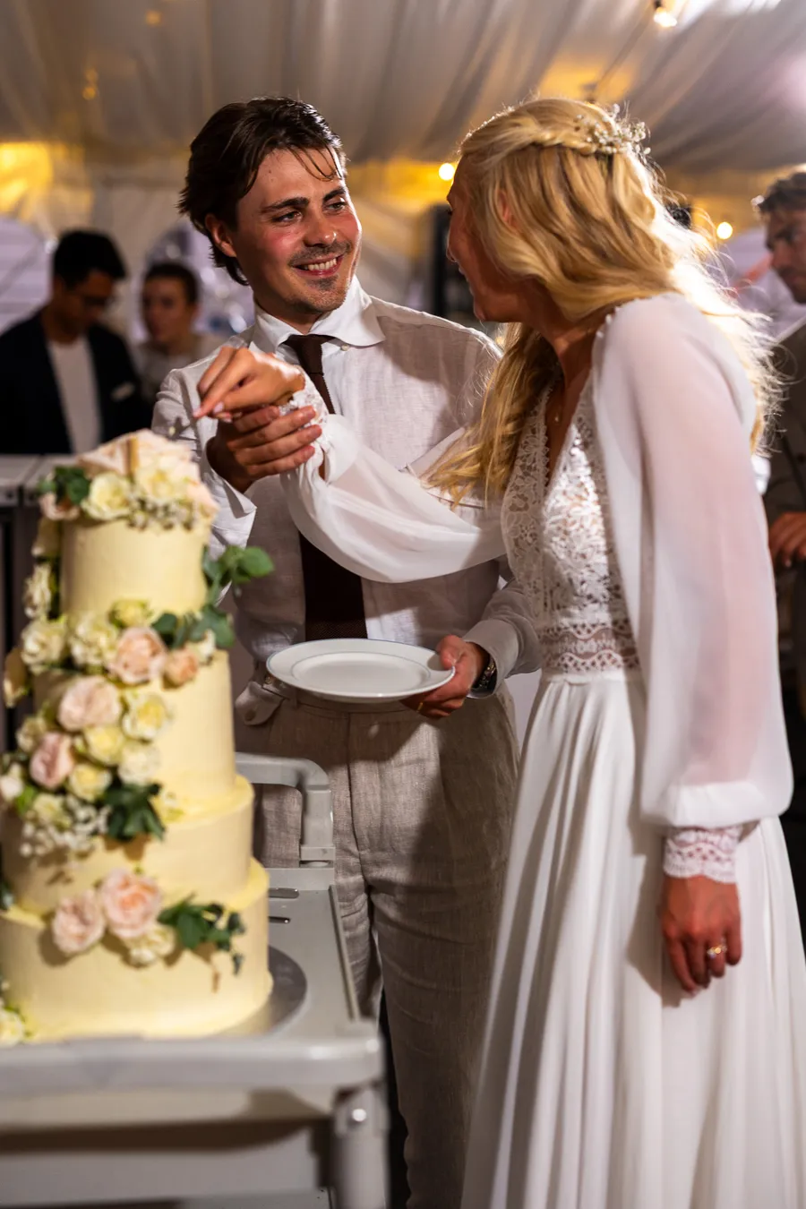 Tonje og Carl kutter bryllupskaken i marquee-tent — flerlags kake med blomster