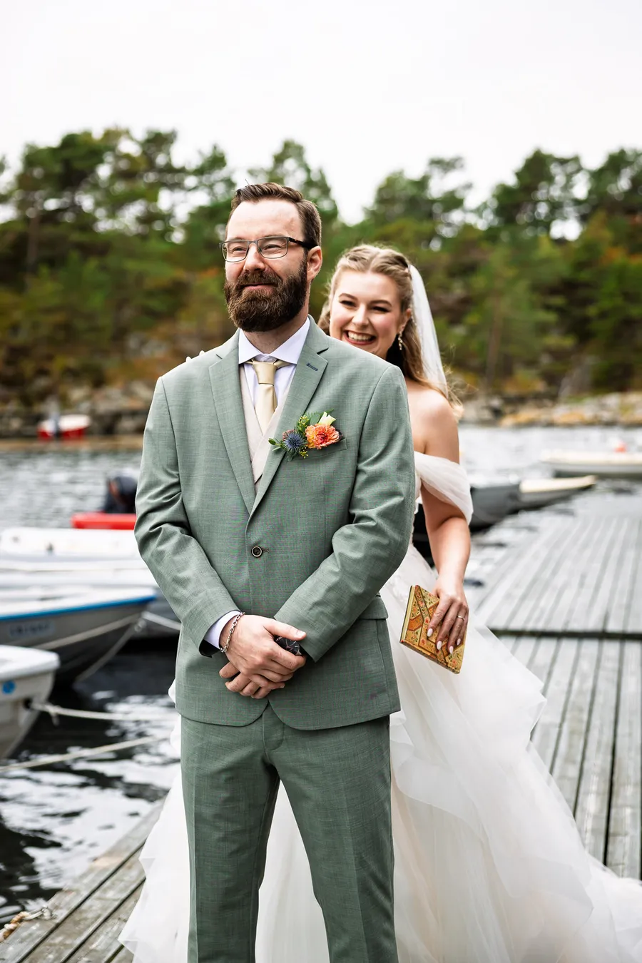Brudgom venter på first look på brygge på Tromøy mens bruden kommer bak ham