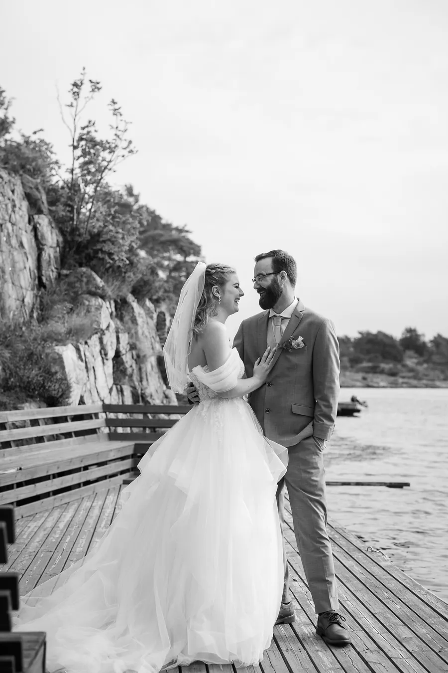 Brudepar ler sammen på trebrygge i sortvitt — bryllupsfotograf Arendal