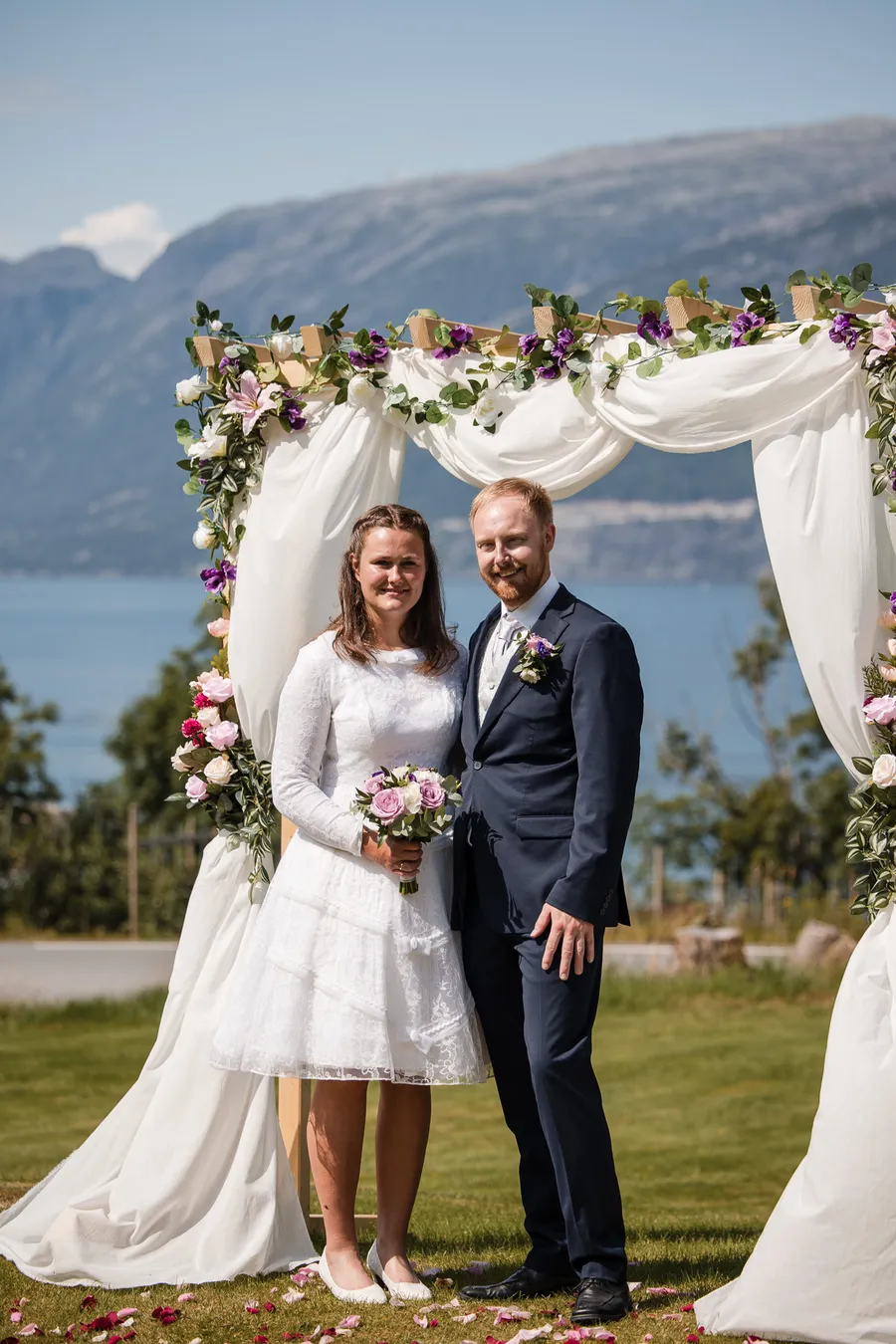 Kristine og Lars under blomsterbuen med Hardangerfjorden bak