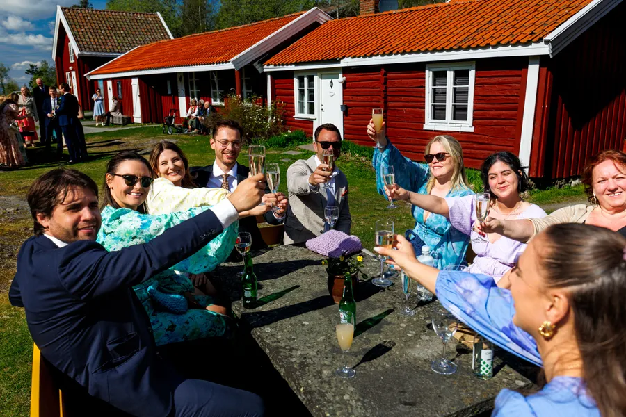 Skål med bryllupsfølget utenfor de røde tømmerstuene